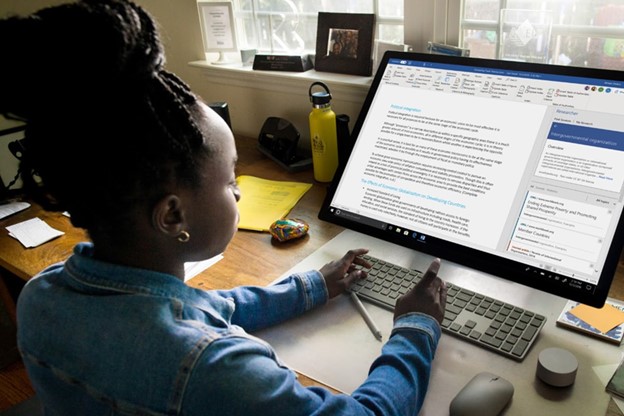 Young person using a wireless keyboard to work on a document in Microsoft Word on a large desktop monitor